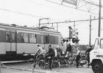 171066 Gezicht op de gesloten spoorwegovergang in de Van der Valk Boumanlaan te Woerden, met wachtende scholieren op de ...